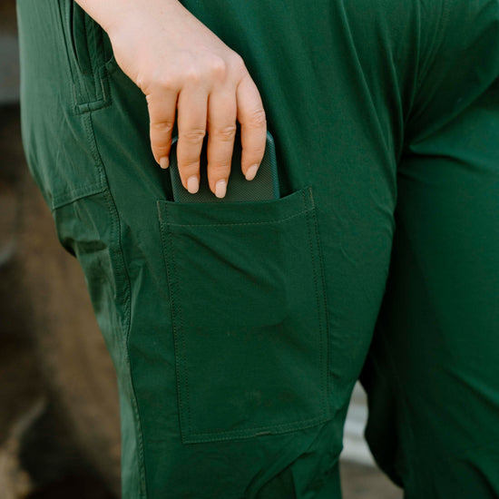 Person wearing green overalls with a close-up of a pocket.