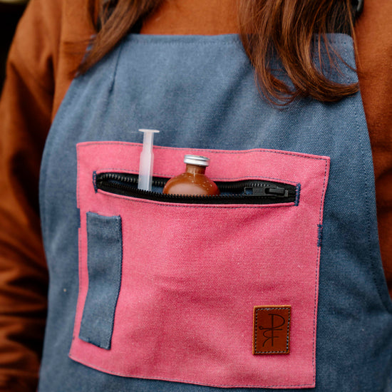 Person wearing a blue overalls with pink pocket containing tools.